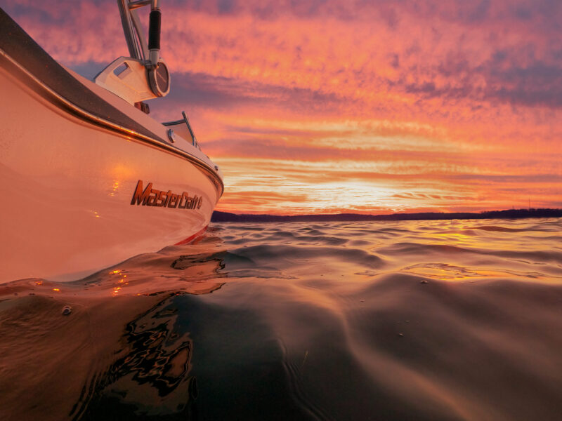 mastercraft boat on water in front of sunset