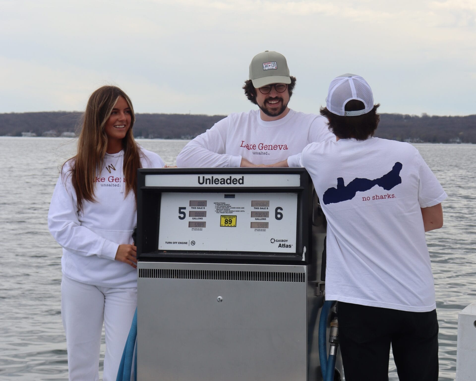 Three people standing around a boat gas pump
